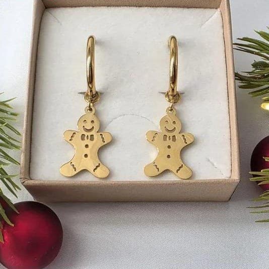 Originalfoto: goldene Lebkuchenmann-Ohrringe in einer Geschenkbox mit Tannenzweigen