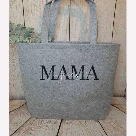 Originalfoto: graue Filztasche mit Aufdruck MAMA und Namen vor einer Holzwand
